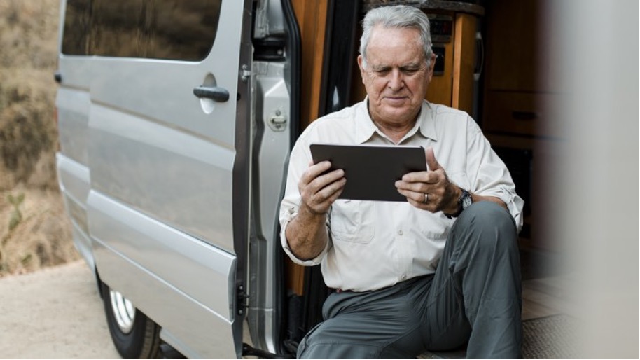 old man looking in tablet screen while sitting in RV 