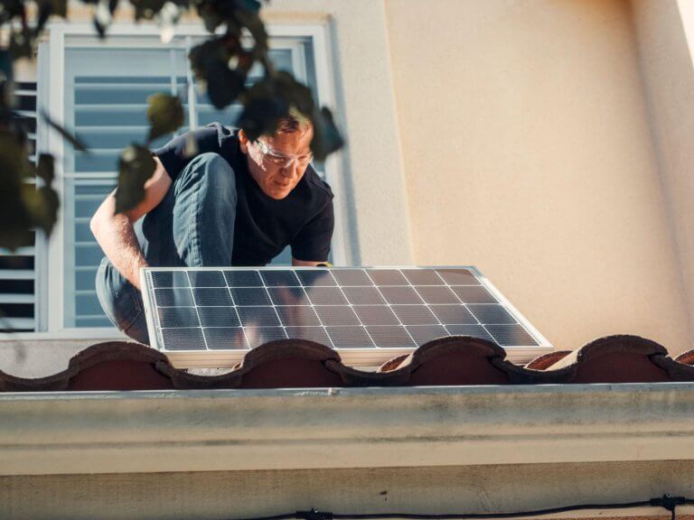 A person installing a solar panel on a roof